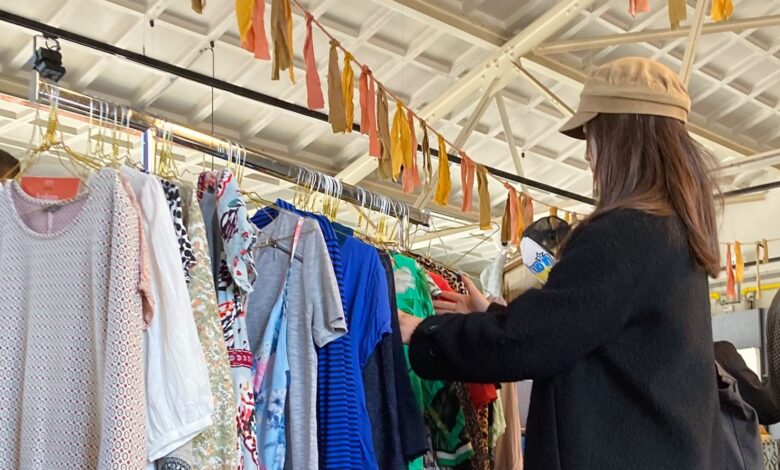 Bezoeker bladert door tweedehands kleding tijdens de kledingruil op het Achtergracht Festival in Zwolle