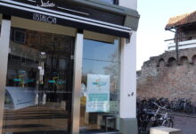 Ingang van IJssalon Salute in Zwolle met poster over heropening van het ijsseizoen.