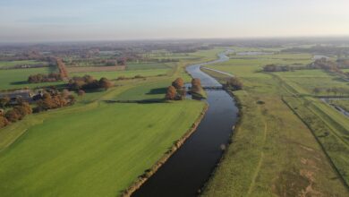 Een foto van de Vecht met de dijk op de voorgrond, rustige lucht, en een duidelijk zicht op het dijktraject tussen Zwolle en Dalfsen.