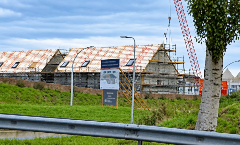 Bouwproject in Zwolle met woningen in aanbouw, steigers en een bouwkraan.